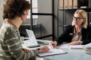 Woman wearing neck brace sits across table from lawyer to discuss personal injury case