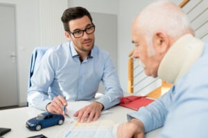 A car accident lawyer explains average settlement timeline to man in neck brace.