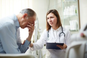 Man holds head after doctor informs him he was injured due to medical malpractice