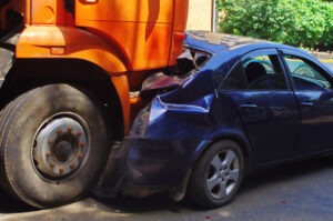 a large orange truck smashed into a blue compact car after a rear-end collision