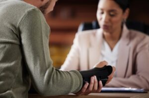 A man holding his wrist, which is in a brace, and speaking with a product liability lawyer in Hartford, CT.