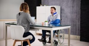 An injured man in a wheelchair, with his arm in a sling and wearing a neck brace, discussing his case with an experienced personal injury lawyer in Hartford.