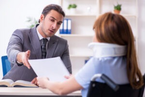 An injured woman in a wheelchair with a neck brace meeting with an experienced truck accident lawyer in East Hartford.