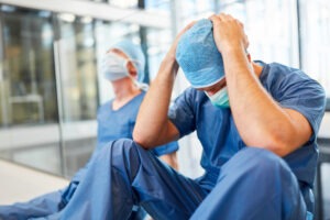 A pair of frustrated doctors sit on the floor. Hire an East Hartford medical malpractice lawyer now.