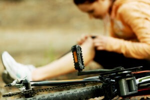 Woman sits on ground next to bicycle after accident in Hartford.