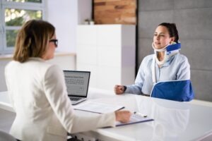 An injured woman with a neck brace and an arm sling speaking with a catastrophic injury lawyer in Granby.