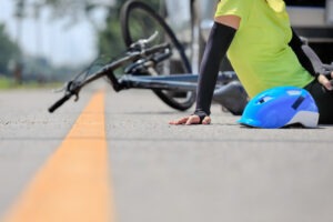 Bicycle accident victim sits on ground next to bike and vehicle in Norwich