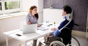 An injured man in a wheelchair with a neck brace and an arm sling speaking with a pedestrian accident injury lawyer in Connecticut.