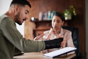 An injured man with a wrist brace speaking with a workers’ compensation lawyer in Hartford.