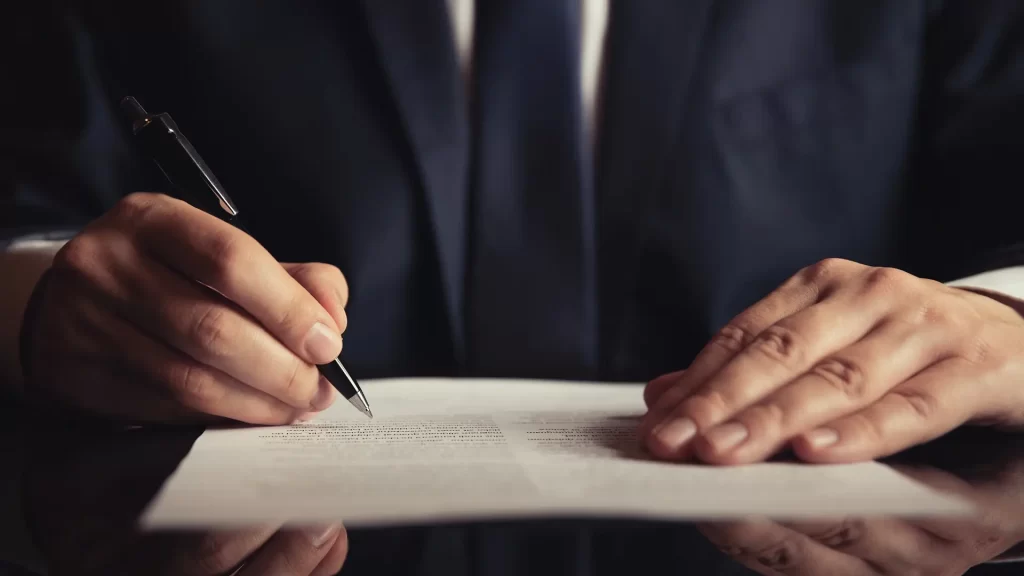 Lawyer signing legal documents at a desk
