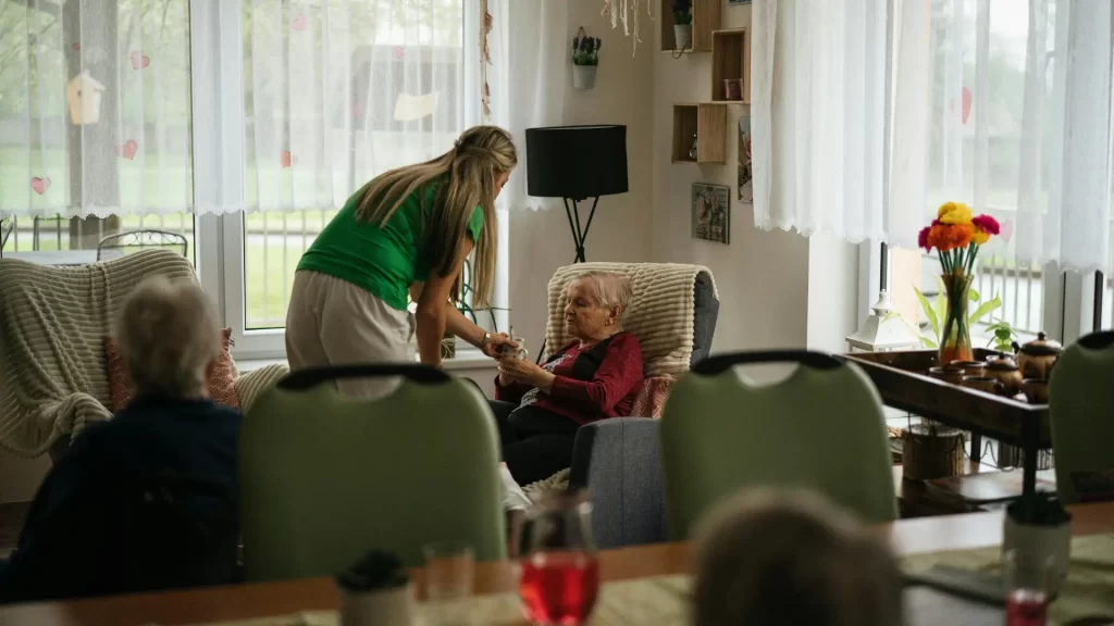 Caregiver assisting elderly woman in a nursing home