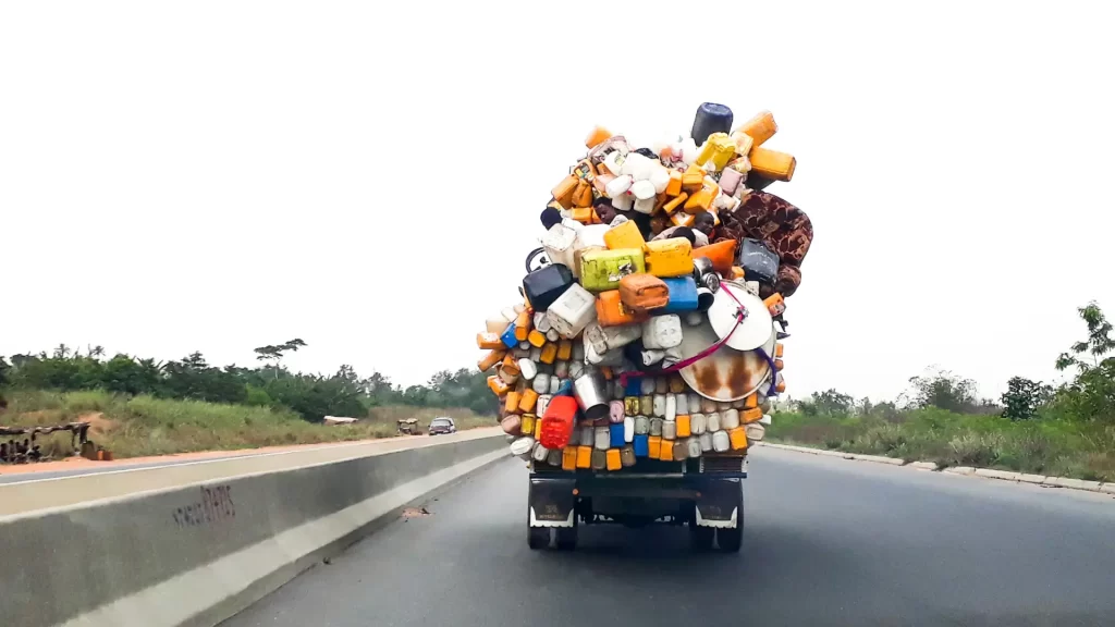 Overloaded truck carrying large pile of goods on road