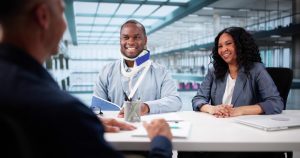 A man with a neck brace sits next to his wife and asks a lawyer if it is worth getting an attorney for a car accident